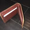 A Genuine Ostrich Skin Leather Men's Bifold Wallet Made In USA - Best Prices sitting on a wooden floor.